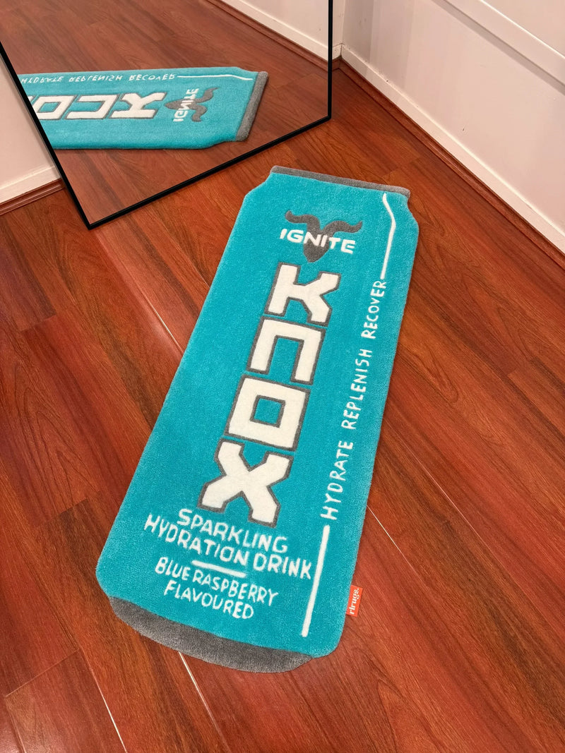 Handmade turquoise rug shaped like a drink can with blue raspberry design on wooden floor