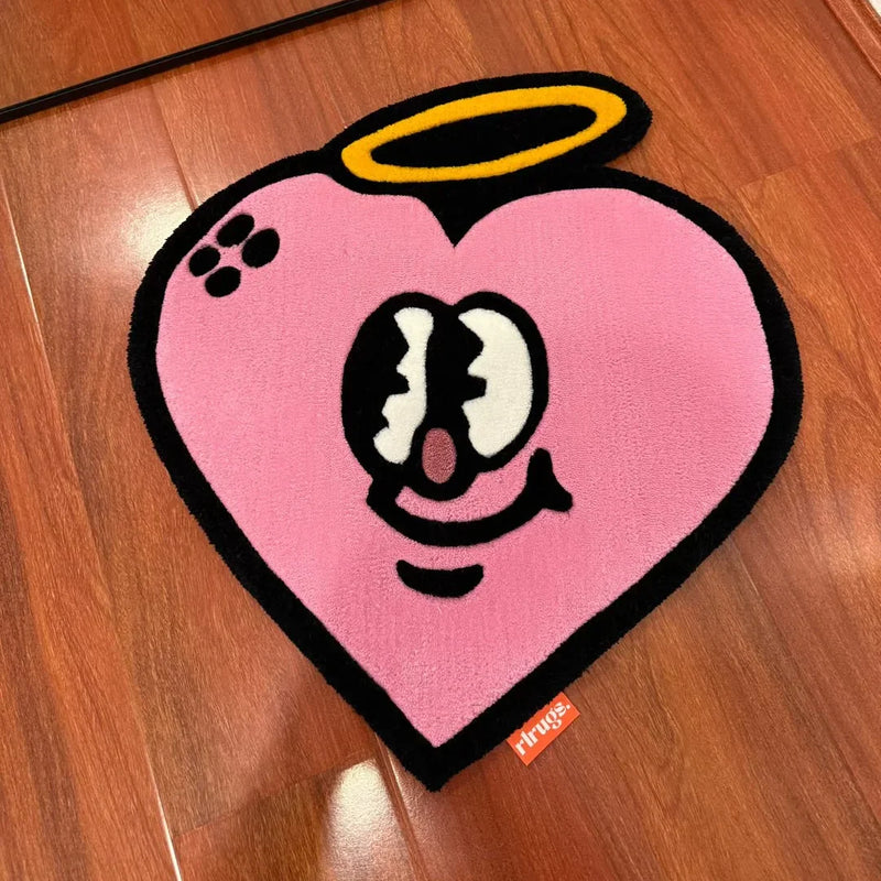 Pink heart-shaped tufted rug with cartoon face and halo on wooden floor