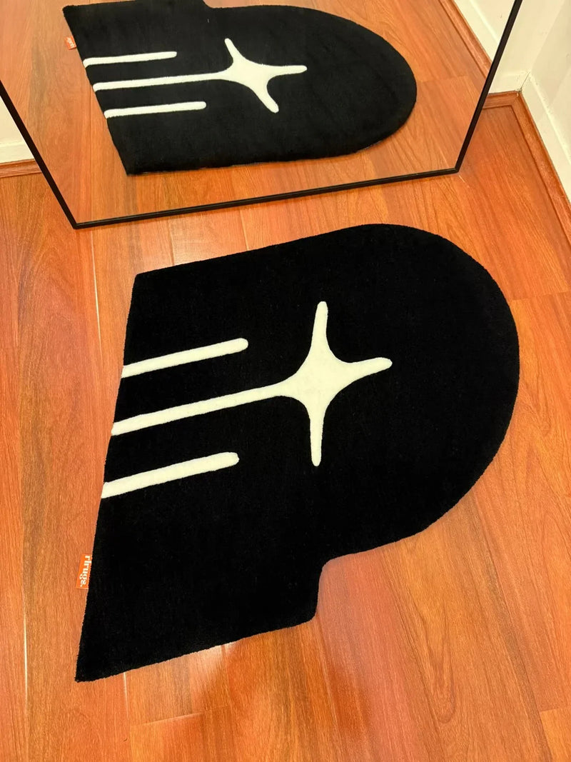 Handmade black tufted rug with abstract white star design on wooden floor, reflected in mirror