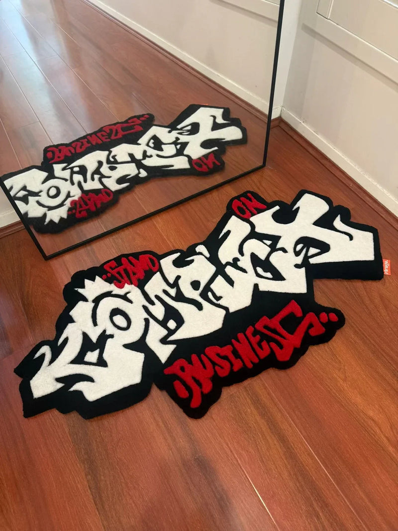 Handmade tufted rug with bold graffiti lettering in black, white and red on wooden floor