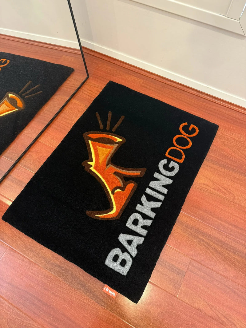 Handmade tufted rug with orange dog graphic and 'BARKING DOG' text on wood floor