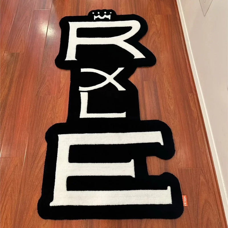 Handmade black and white tufted rug with bold letters and crown design on wood floor