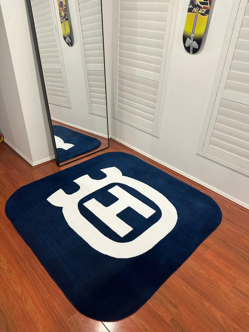 Handmade navy blue rug with bold white H logo, modern decor on wooden floor