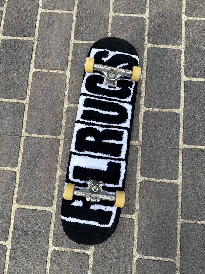 Handmade black and white tufted rug styled as a skateboard on outdoor paving