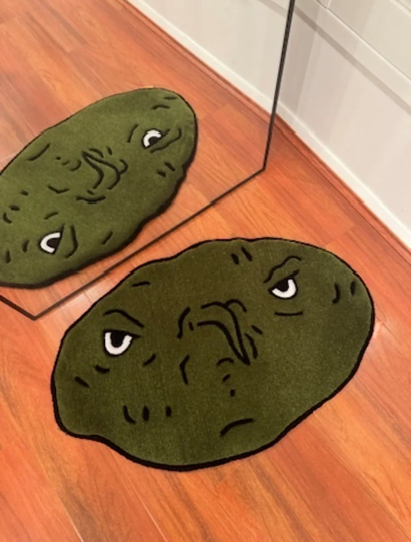 Handmade green tufted rug with cartoon grumpy face on wooden floor by a mirror