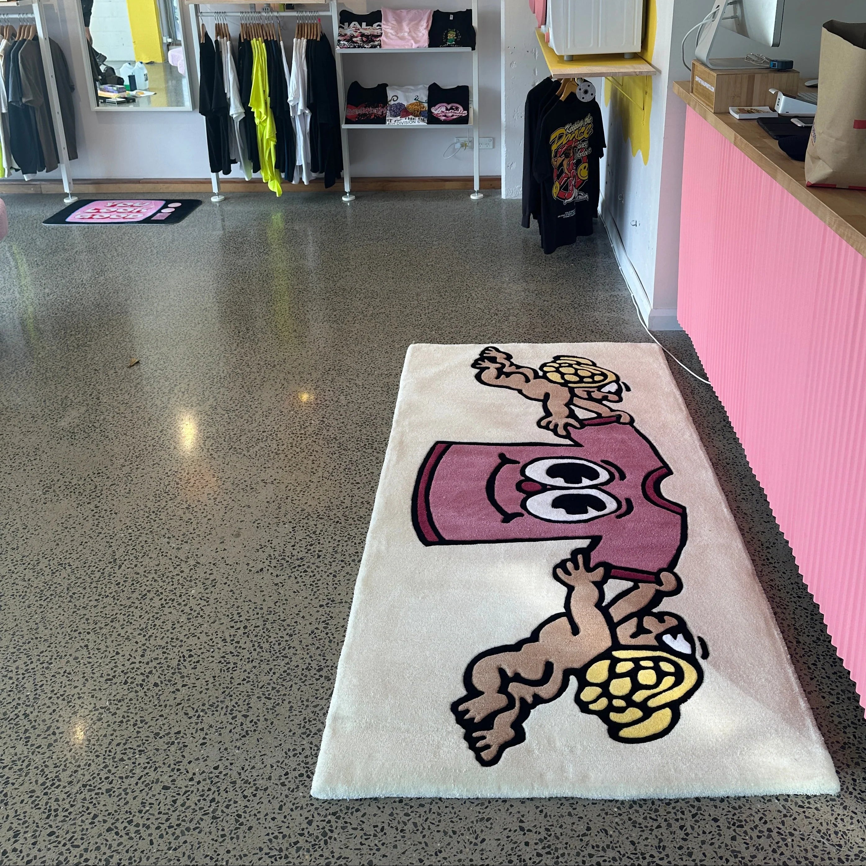 Handmade tufted rug with cartoon cherubs and pink face design in a modern boutique store