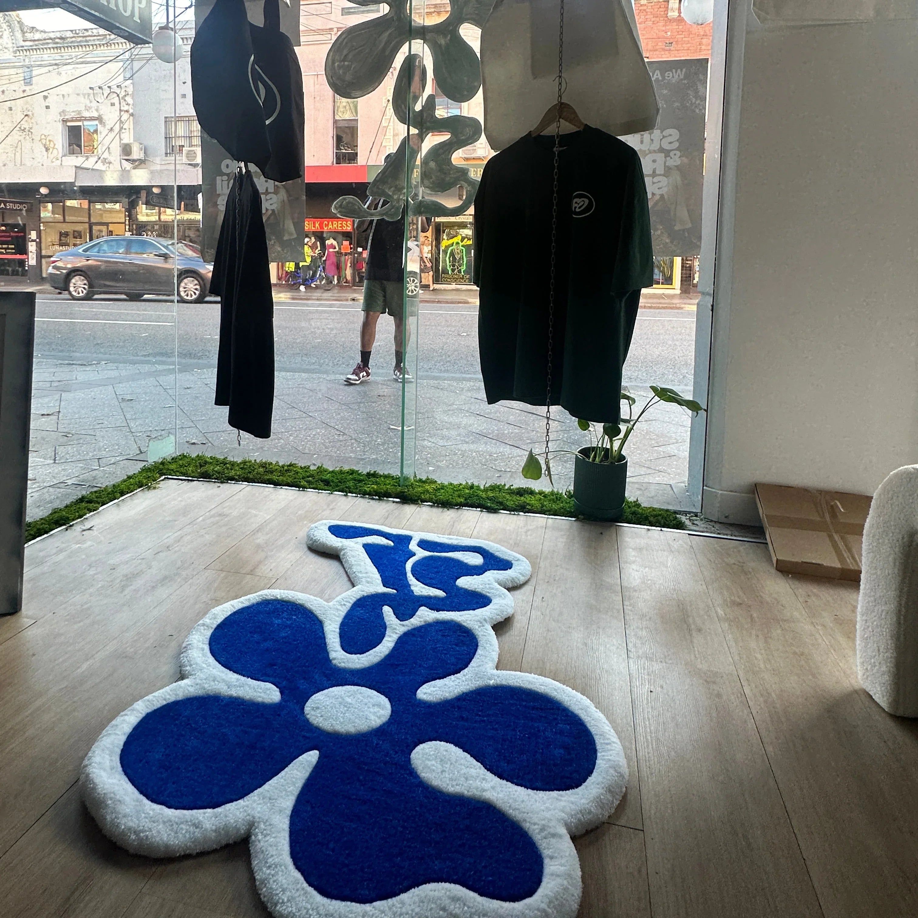 Handmade tufted rug with blue and white flower design displayed in a modern store window