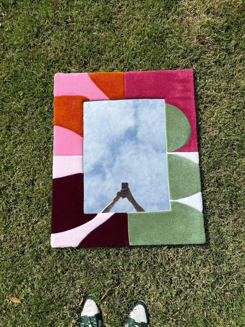 Handmade tufted multicolour rug mirror with geometric design on grass outdoors
