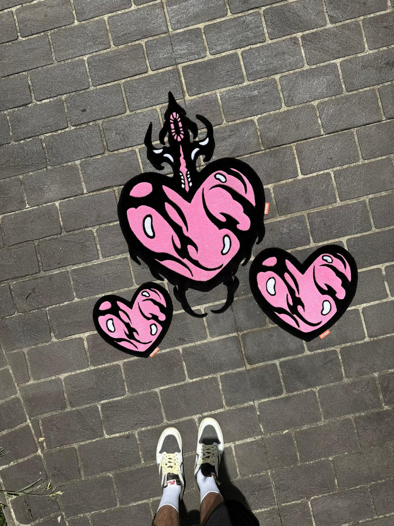 Handmade tufted pink heart rugs with black outlines and flame details on outdoor pavers
